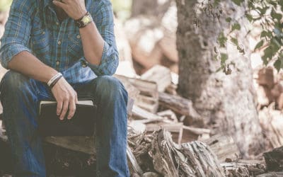 Man sitting alone outside with Bible