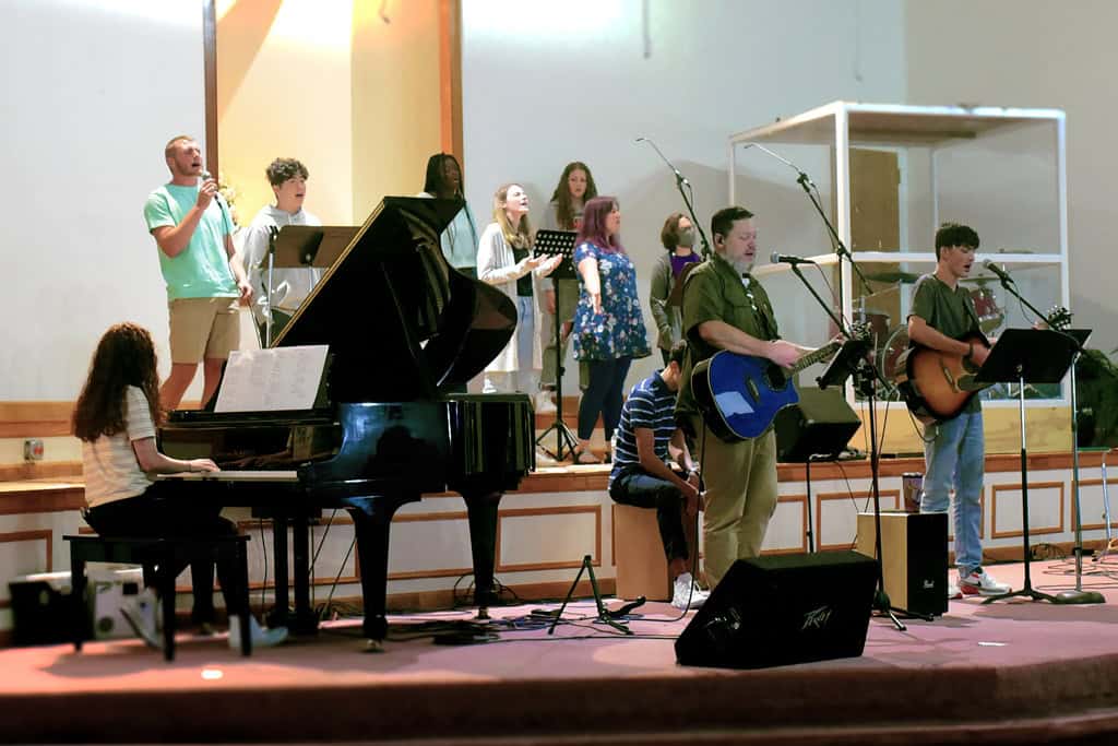 Sunday Worship Music at Agape Church The Agape Church worship team on stage during a Sunday service, featuring vocalists, a grand piano, and acoustic guitars.